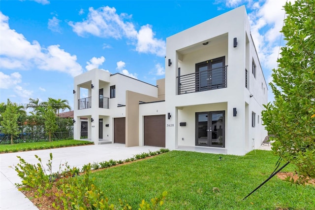 modern home featuring a garage, a balcony, a front yard, and french doors