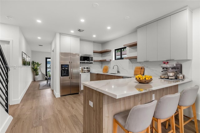 kitchen with white cabinetry, a breakfast bar, kitchen peninsula, and appliances with stainless steel finishes