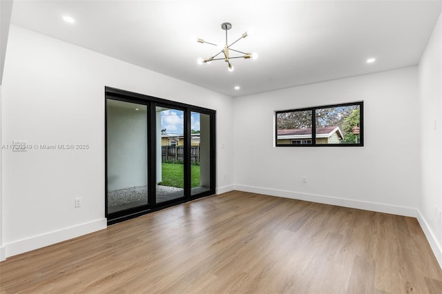 unfurnished room featuring light hardwood / wood-style flooring, a chandelier, and plenty of natural light