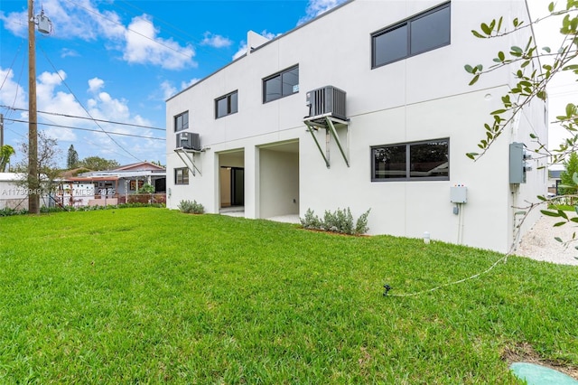 back of property with an AC wall unit, central AC unit, and a lawn