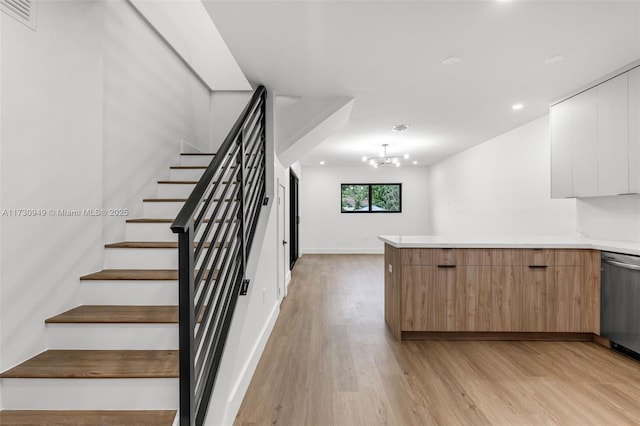 stairs with wood-type flooring and a notable chandelier