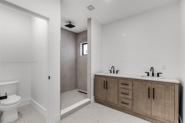 bathroom featuring vanity, a tile shower, and toilet