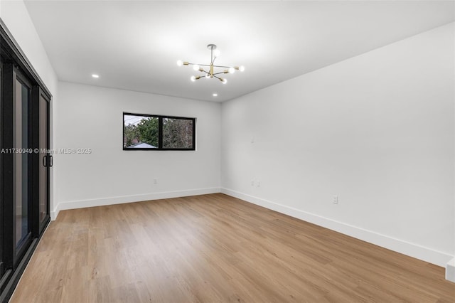 spare room with light hardwood / wood-style flooring and a notable chandelier