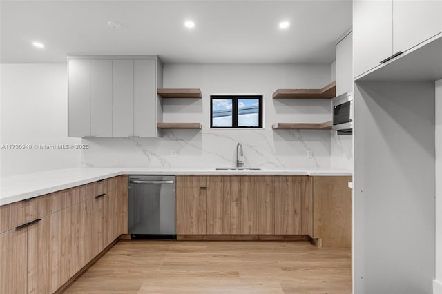 kitchen with sink, light hardwood / wood-style flooring, appliances with stainless steel finishes, decorative backsplash, and white cabinets