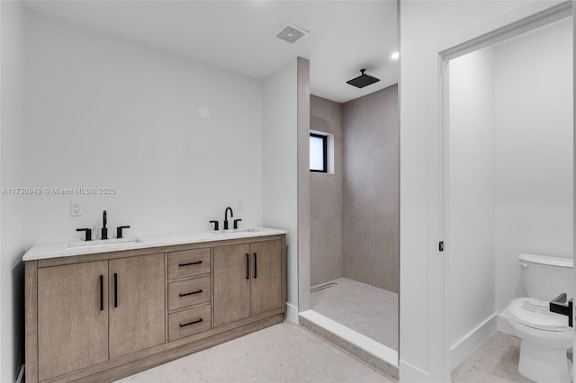 bathroom with vanity, tiled shower, and toilet