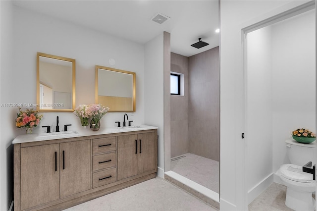 bathroom featuring vanity, tiled shower, and toilet