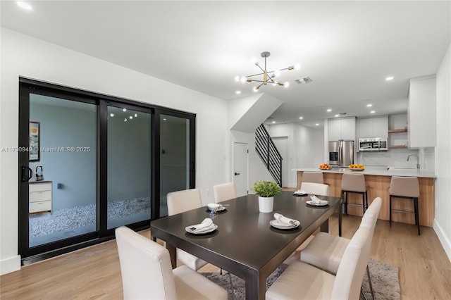 dining area with sink, a chandelier, and light hardwood / wood-style flooring