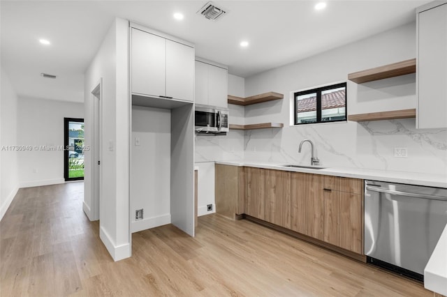 kitchen with white cabinetry, appliances with stainless steel finishes, sink, and light hardwood / wood-style flooring