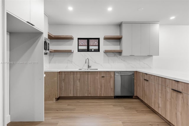 kitchen featuring stainless steel appliances, sink, light hardwood / wood-style flooring, and white cabinets