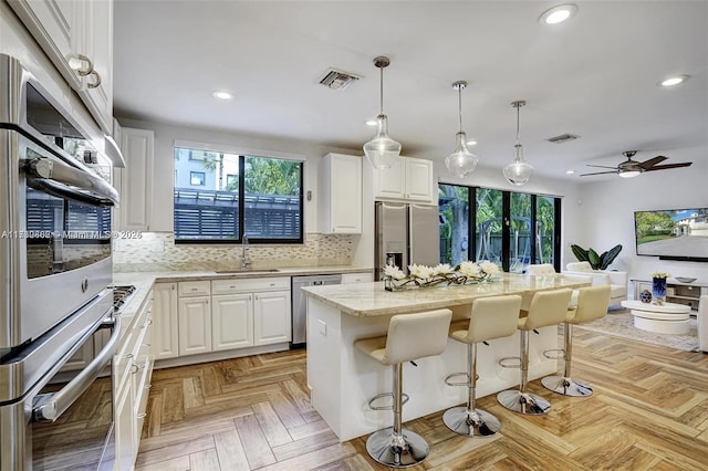 kitchen featuring stainless steel appliances, a kitchen island, and white cabinets