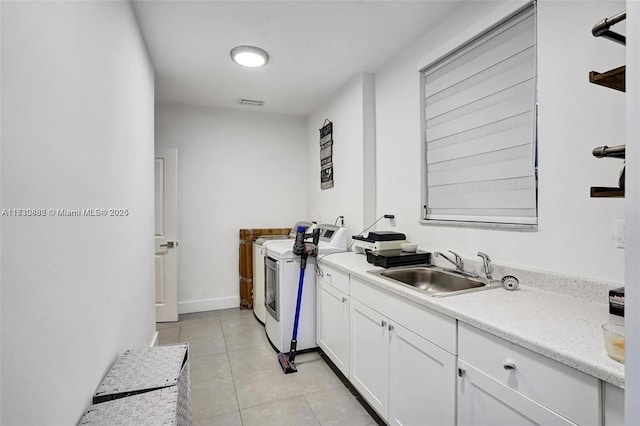 laundry room featuring cabinets, sink, light tile patterned floors, and independent washer and dryer