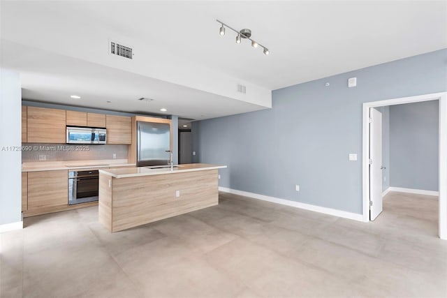 kitchen featuring sink, appliances with stainless steel finishes, a kitchen island with sink, and tasteful backsplash