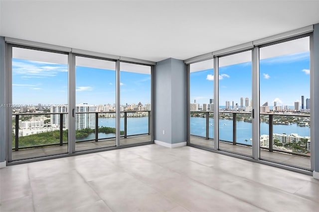 unfurnished room featuring a wall of windows, a water view, and a wealth of natural light