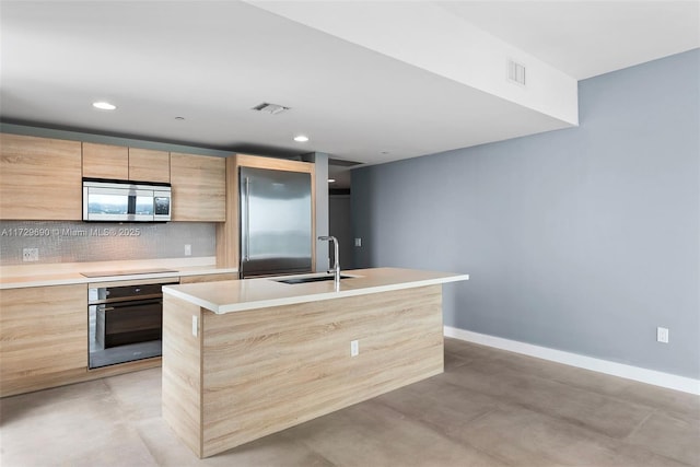 kitchen featuring sink, stainless steel appliances, a center island with sink, and tasteful backsplash