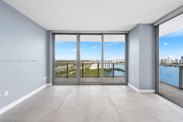 unfurnished room featuring a wall of windows, a water view, and a healthy amount of sunlight