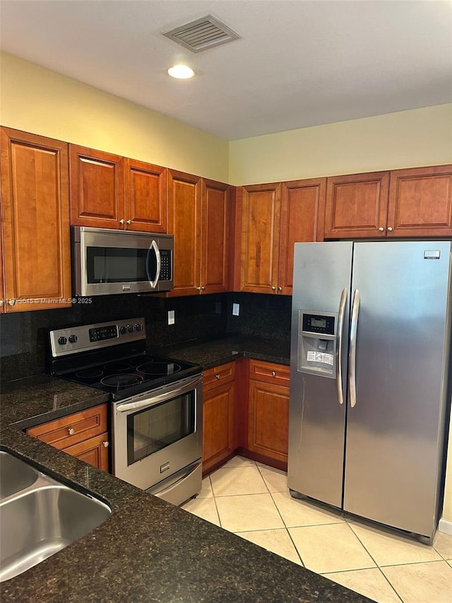 kitchen with sink, light tile patterned floors, appliances with stainless steel finishes, and decorative backsplash