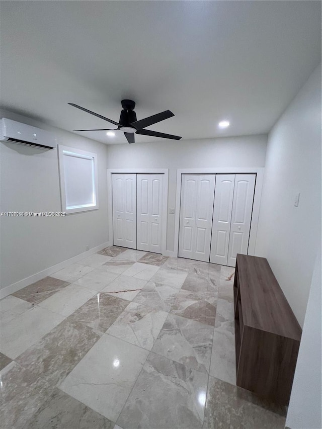 unfurnished bedroom featuring multiple closets, ceiling fan, and a wall unit AC