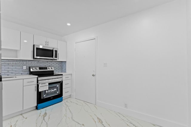 kitchen with stainless steel appliances, white cabinetry, and backsplash