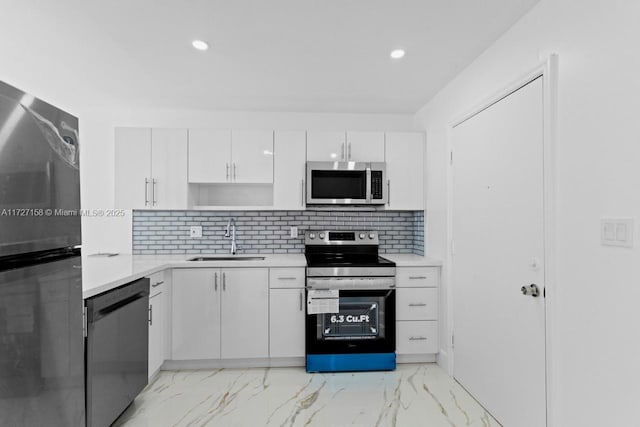 kitchen with sink, white cabinets, tasteful backsplash, and appliances with stainless steel finishes