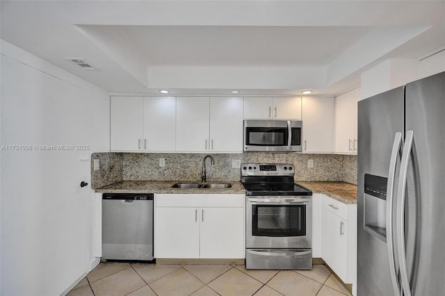 kitchen featuring stone counters, appliances with stainless steel finishes, decorative backsplash, white cabinets, and sink