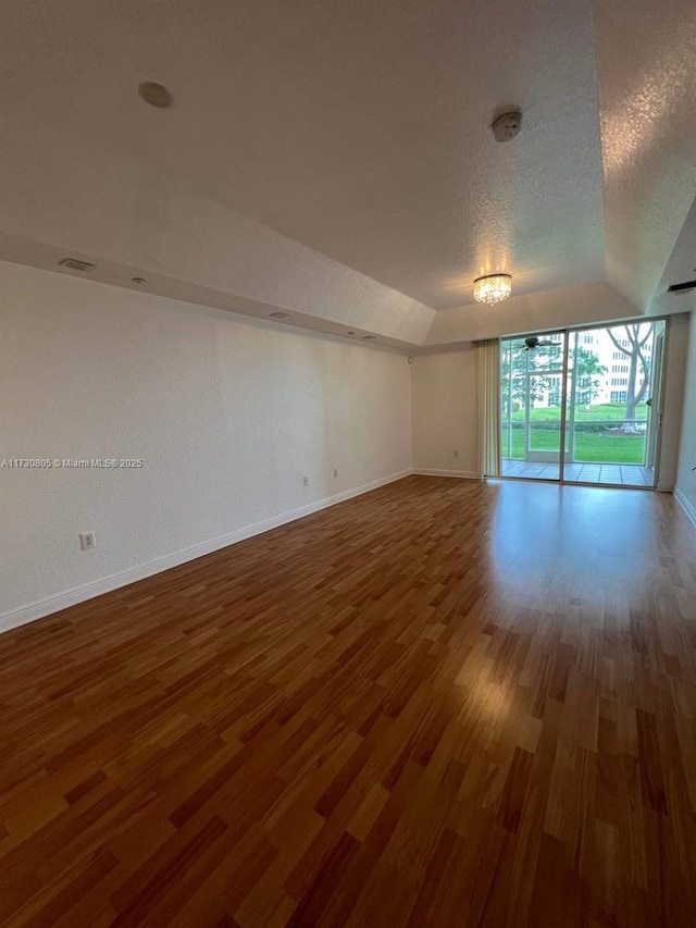 spare room with dark wood-type flooring, a textured ceiling, and vaulted ceiling