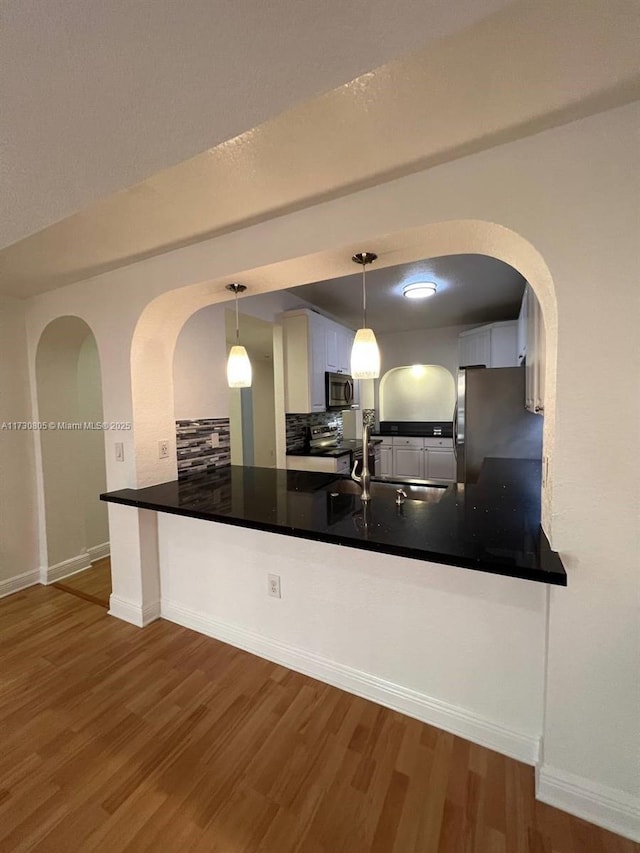 kitchen featuring pendant lighting, white cabinetry, stainless steel appliances, sink, and kitchen peninsula