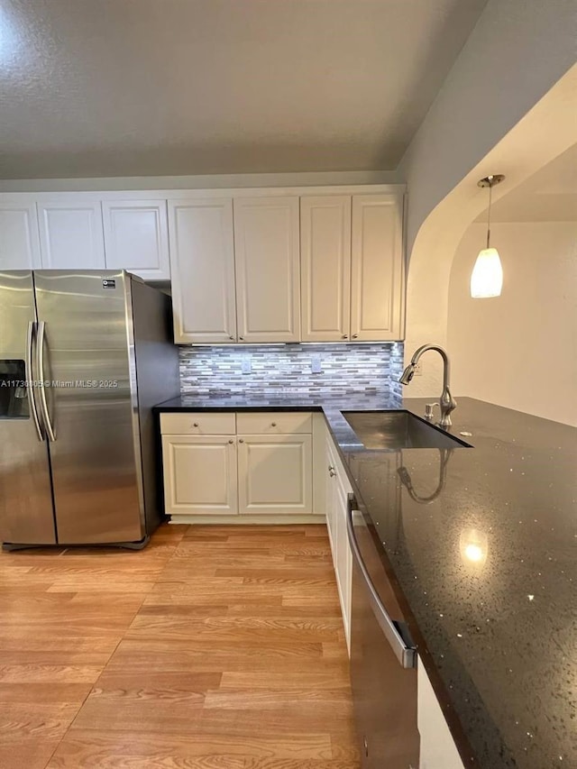 kitchen featuring white cabinets, appliances with stainless steel finishes, decorative light fixtures, tasteful backsplash, and sink