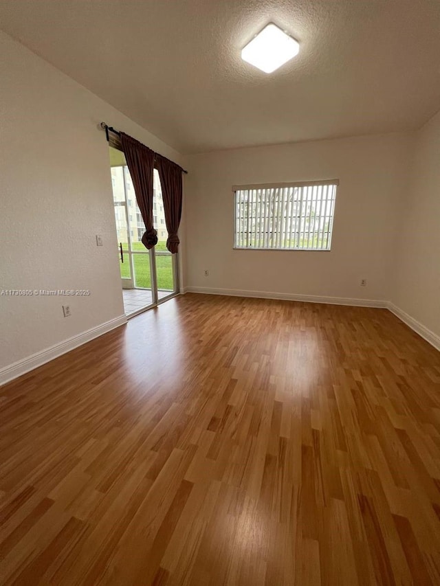 spare room with wood-type flooring, plenty of natural light, and a textured ceiling