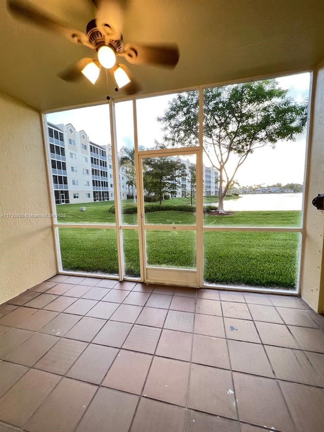 unfurnished sunroom featuring a water view and ceiling fan