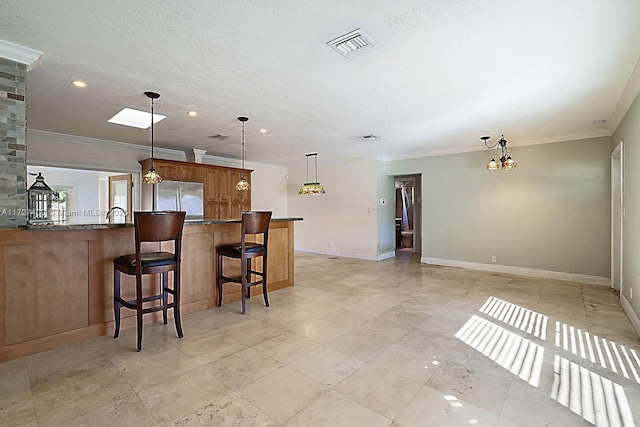 kitchen featuring stainless steel refrigerator, decorative light fixtures, ornamental molding, kitchen peninsula, and a breakfast bar