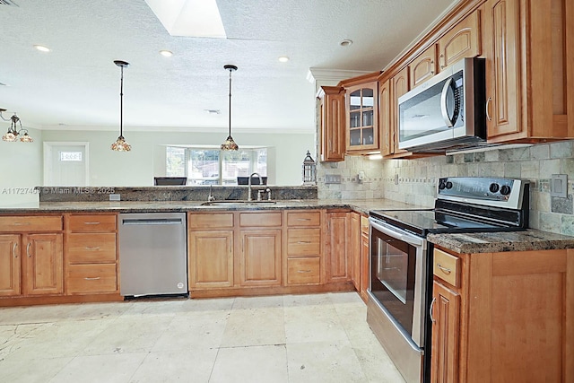 kitchen featuring decorative light fixtures, sink, dark stone counters, and appliances with stainless steel finishes