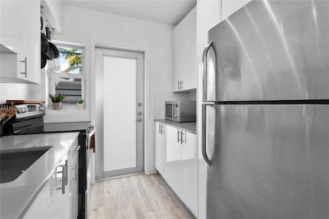 kitchen featuring light hardwood / wood-style floors, decorative backsplash, white cabinets, and stainless steel appliances