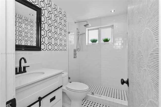 bathroom featuring vanity, toilet, tile walls, and tiled shower