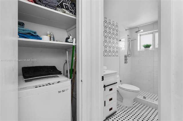 bathroom featuring a tile shower, toilet, and vanity