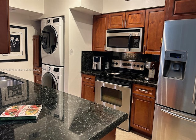 kitchen with sink, stacked washer and dryer, dark stone countertops, decorative backsplash, and stainless steel appliances