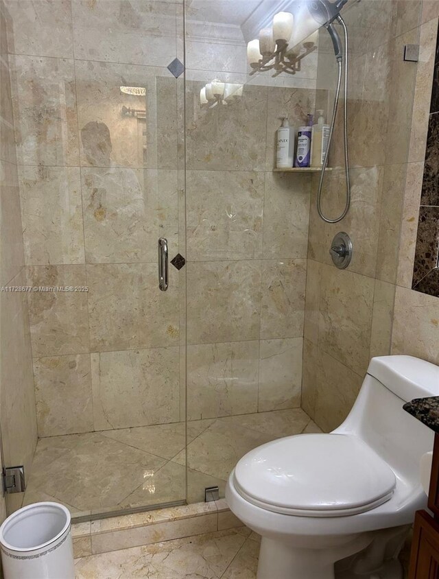 bathroom featuring toilet, a shower with door, and an inviting chandelier