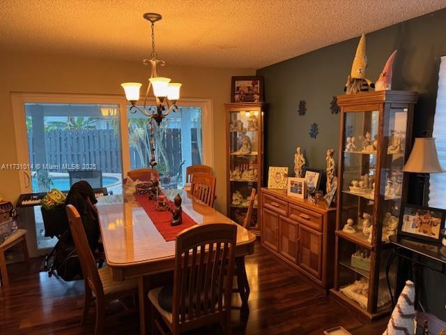 dining room featuring a textured ceiling, dark hardwood / wood-style flooring, and a chandelier