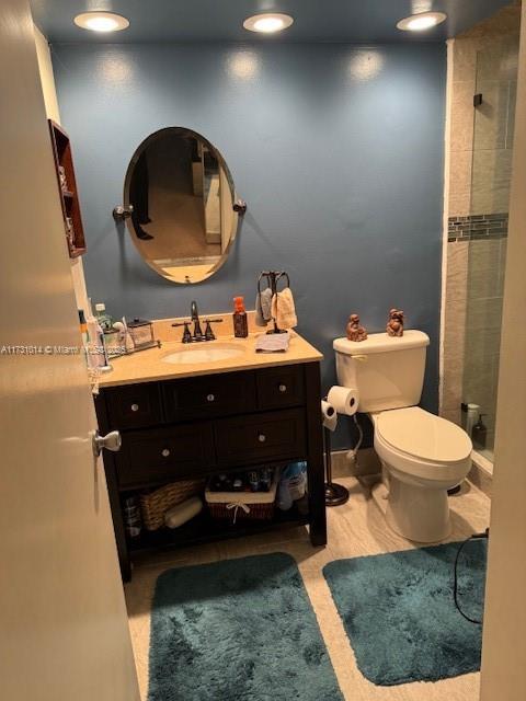 bathroom with toilet, a shower, and vanity