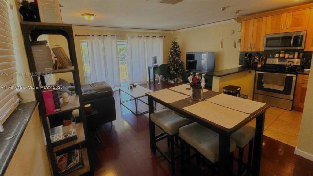 7420 SW 82nd St Unit D207, Miami, FL 33143 - kitchen with crown molding, stainless steel appliances, dark countertops, and dark wood finished floors