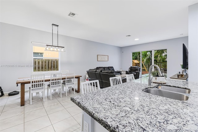 kitchen featuring sink, decorative light fixtures, light tile patterned floors, and light stone countertops