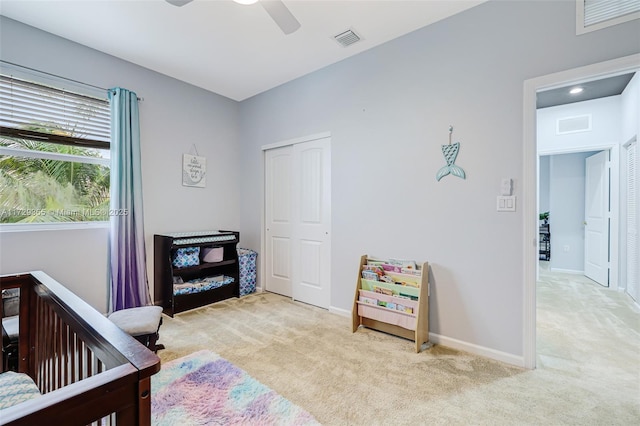 carpeted bedroom featuring ceiling fan, a nursery area, and a closet