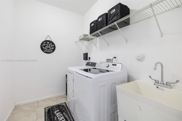 laundry area with sink, washing machine and clothes dryer, and light tile patterned floors