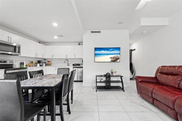 kitchen featuring white cabinets, appliances with stainless steel finishes, tasteful backsplash, and sink