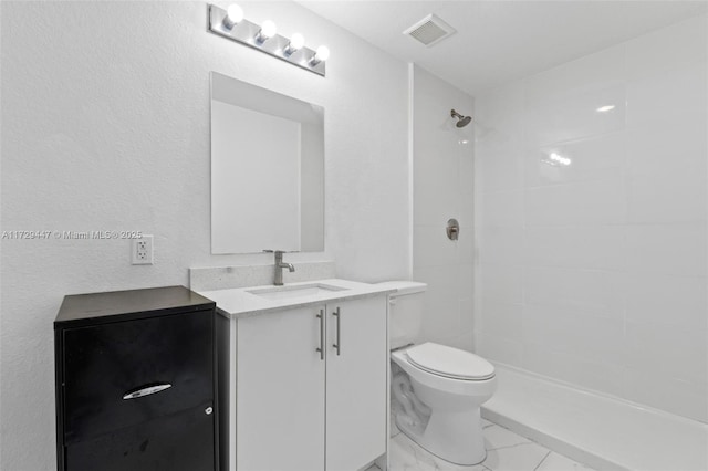 bathroom with vanity, toilet, and a tile shower