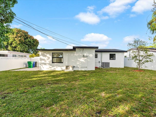 back of house featuring central AC unit and a lawn