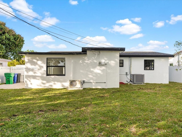 back of property with ac unit, a lawn, and central air condition unit