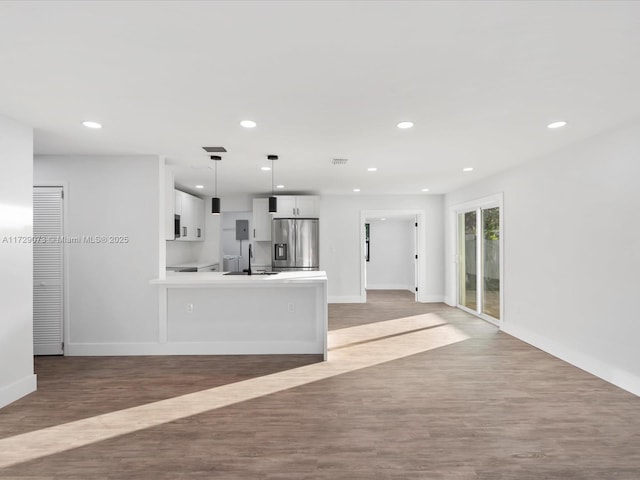 kitchen with stainless steel refrigerator with ice dispenser, pendant lighting, white cabinetry, and light wood-type flooring