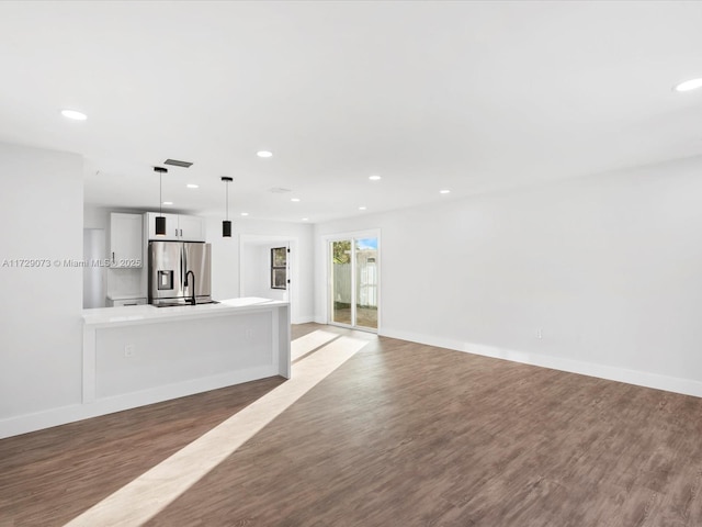 unfurnished living room featuring wood-type flooring and sink