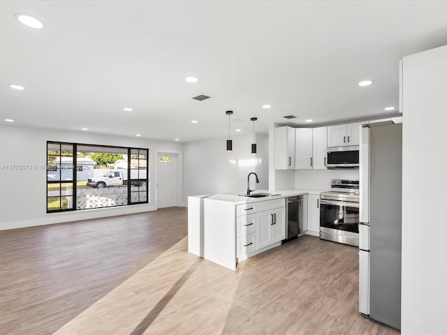 kitchen with white cabinetry, hanging light fixtures, light hardwood / wood-style flooring, and appliances with stainless steel finishes