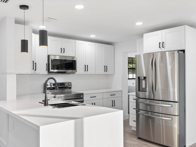 kitchen with kitchen peninsula, pendant lighting, white cabinetry, and appliances with stainless steel finishes